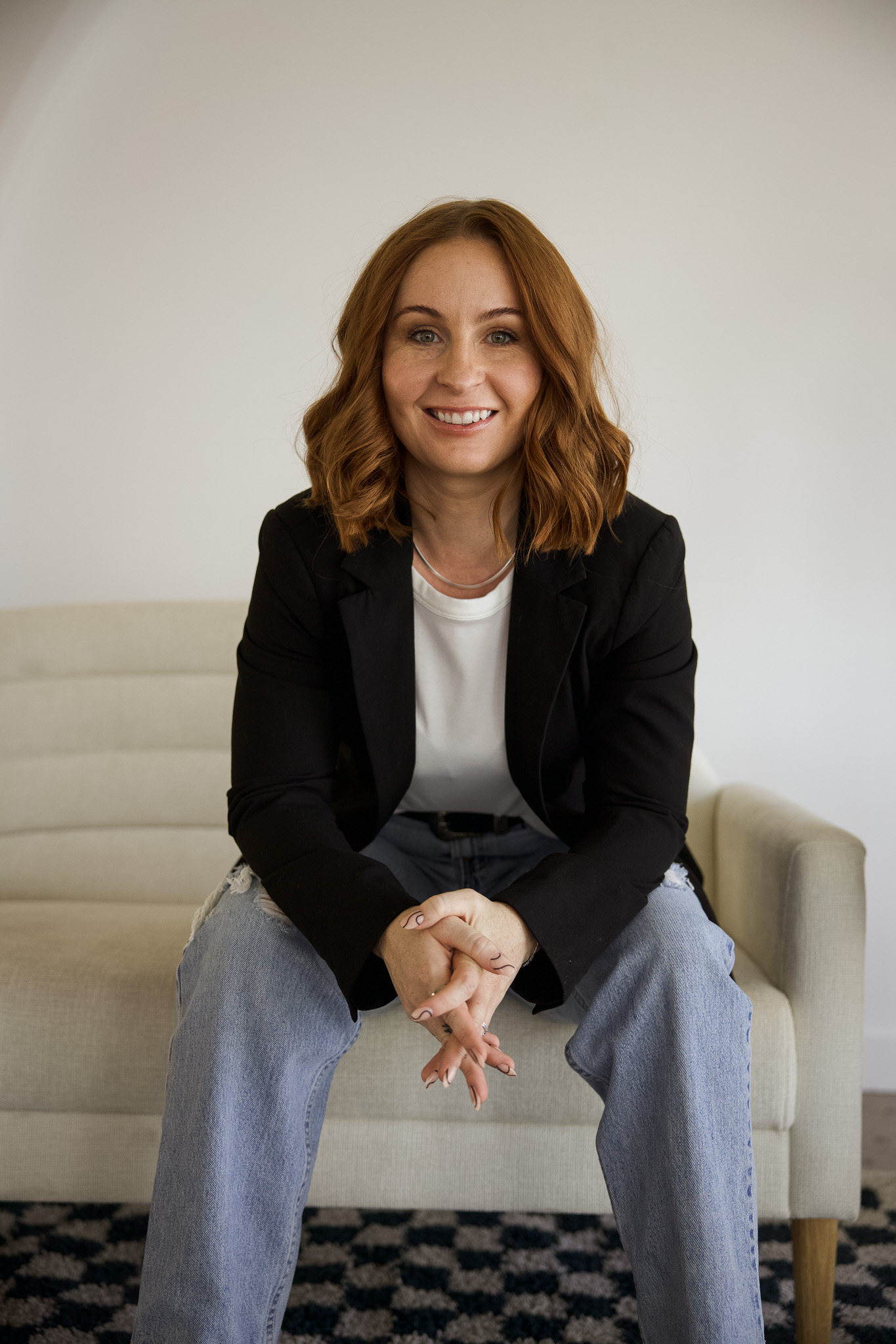 Ash Santana of Sagecrest Communications sits on a white couch.